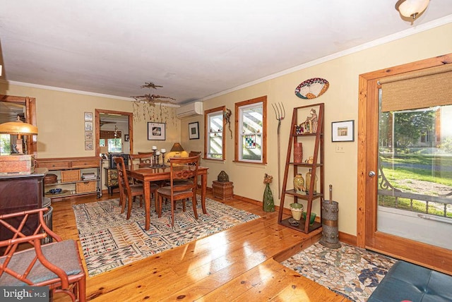 dining room featuring a wall mounted AC, crown molding, plenty of natural light, and wood-type flooring