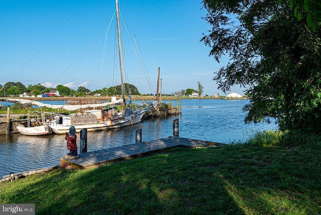 view of dock with a lawn and a water view