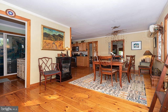 dining room with a wall mounted AC, light hardwood / wood-style flooring, a wood stove, and ornamental molding