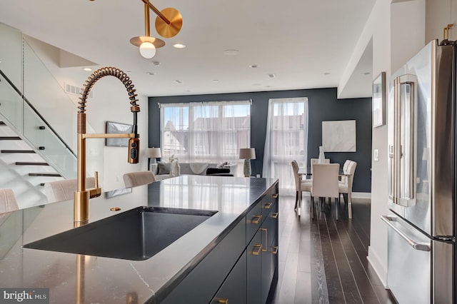 kitchen with high end fridge, dark wood-type flooring, decorative light fixtures, and sink