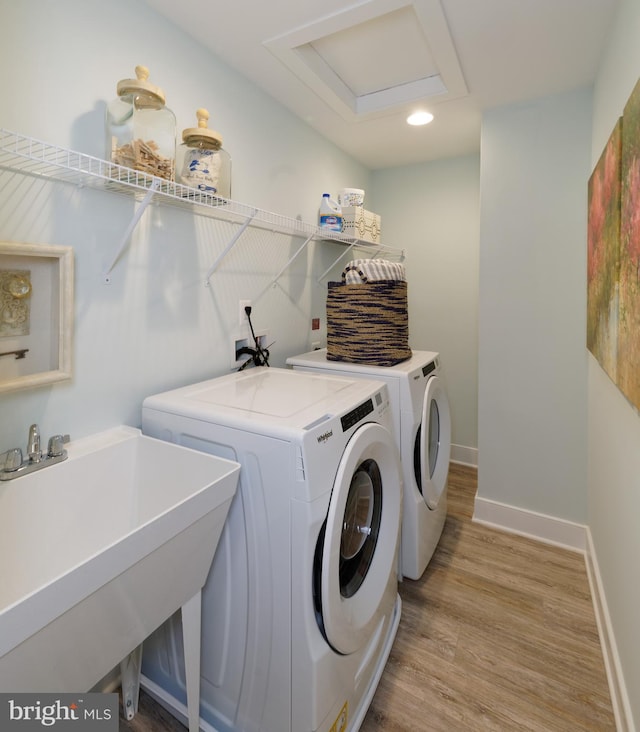 clothes washing area featuring separate washer and dryer, sink, and light hardwood / wood-style floors