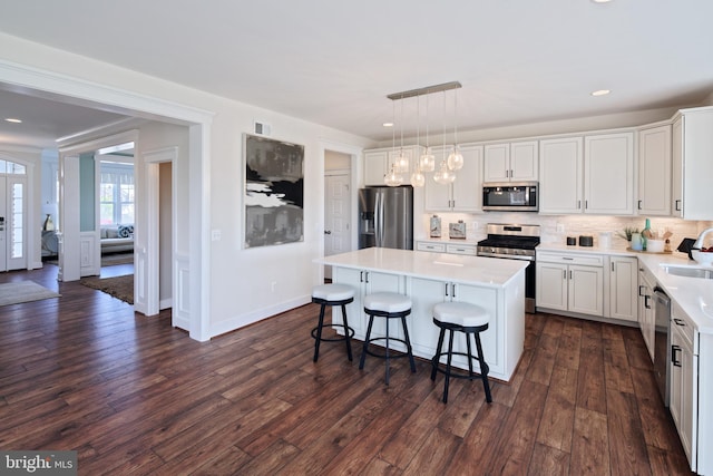 kitchen with white cabinets, pendant lighting, stainless steel appliances, and a kitchen island