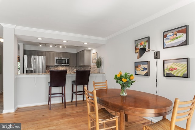 dining area with light hardwood / wood-style flooring and ornamental molding