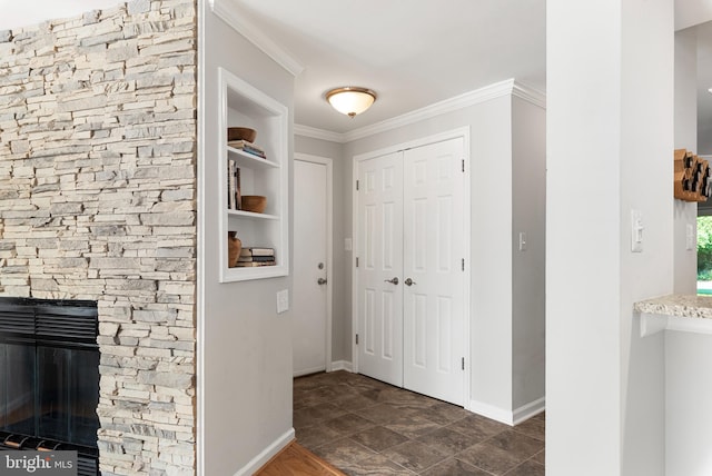 foyer with a stone fireplace and ornamental molding