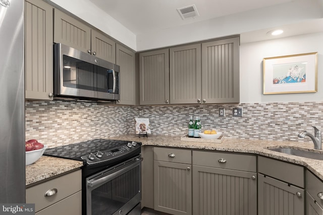 kitchen with stainless steel appliances, gray cabinetry, tasteful backsplash, and sink