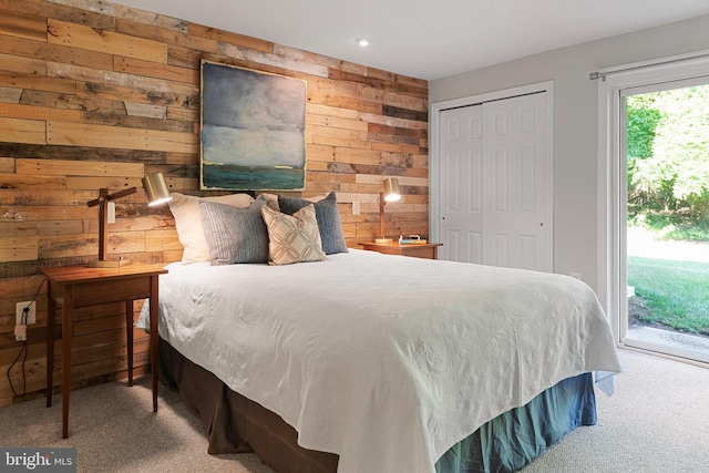 bedroom featuring access to exterior, light colored carpet, a closet, and wooden walls