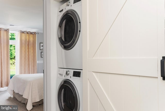 laundry room with crown molding, stacked washer and dryer, and carpet flooring