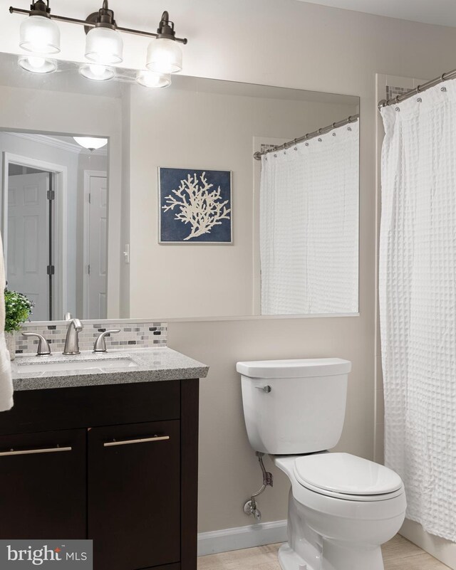 bathroom featuring toilet, vanity, a shower with shower curtain, and tasteful backsplash