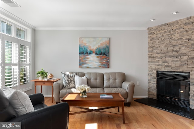 living room featuring light wood-type flooring, crown molding, and a fireplace