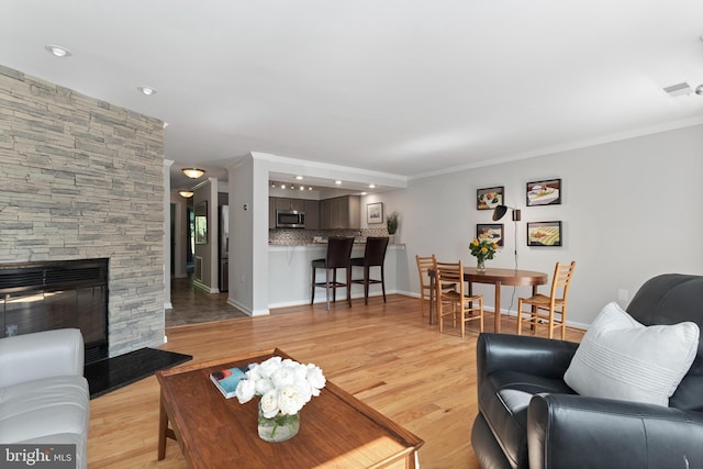 living room with light wood-type flooring, a fireplace, and crown molding