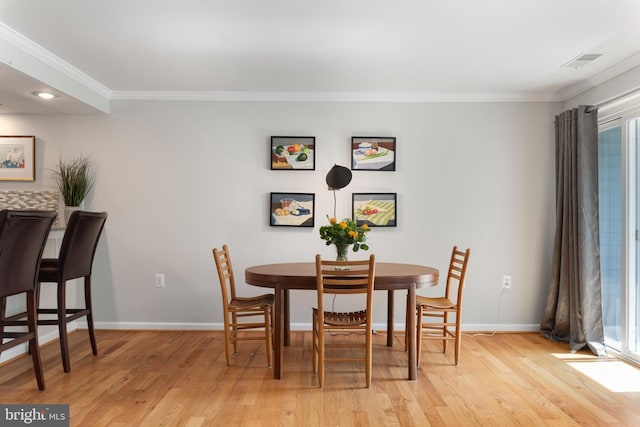 dining room with ornamental molding and light hardwood / wood-style floors