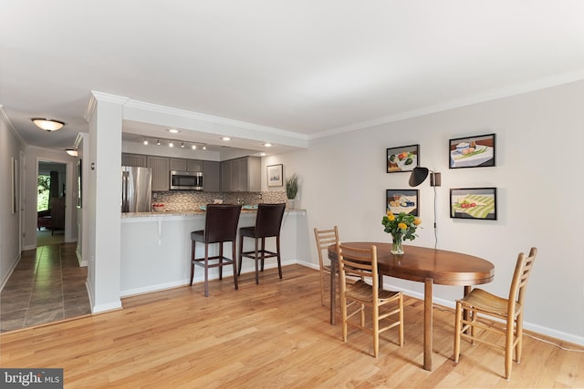 dining room with light wood-type flooring and ornamental molding