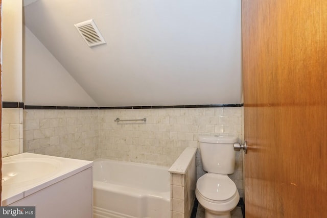 bathroom with lofted ceiling, tile walls, vanity, toilet, and a bath