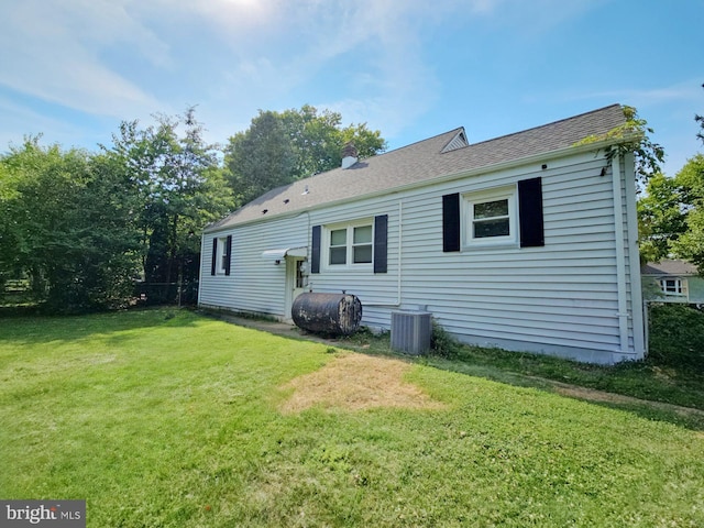 back of property featuring central AC and a lawn