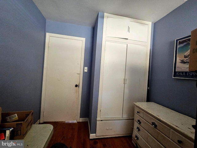 bedroom with dark hardwood / wood-style floors and a closet