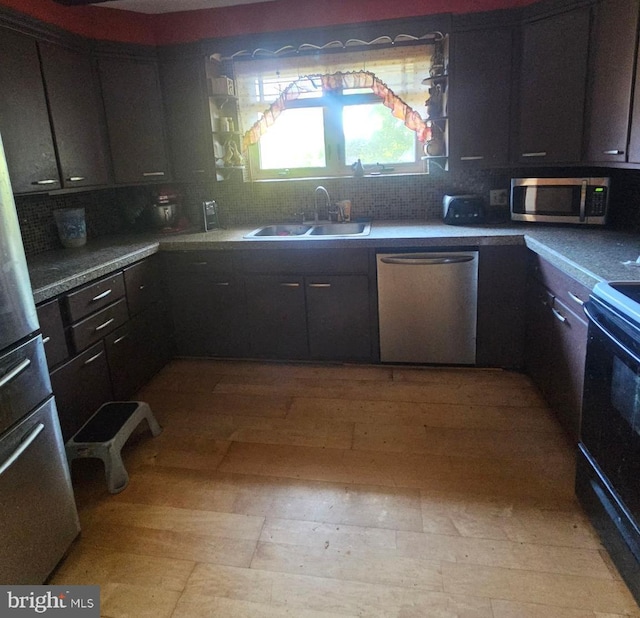 kitchen with appliances with stainless steel finishes, dark brown cabinetry, tasteful backsplash, and sink