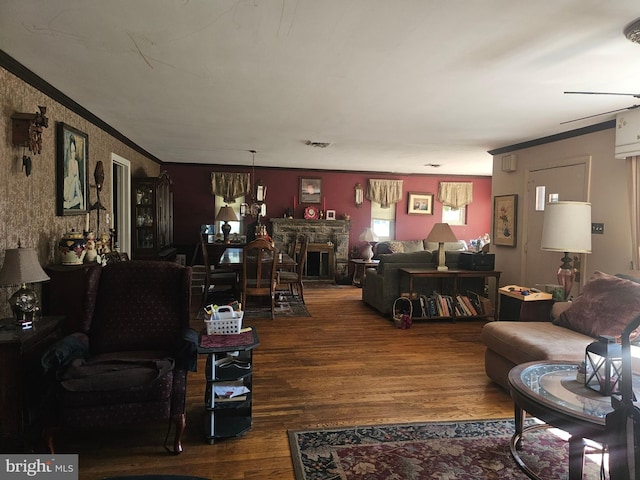 living room with dark hardwood / wood-style flooring, a stone fireplace, and ornamental molding