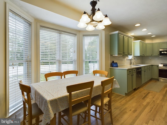 dining area with light hardwood / wood-style flooring, an inviting chandelier, and sink