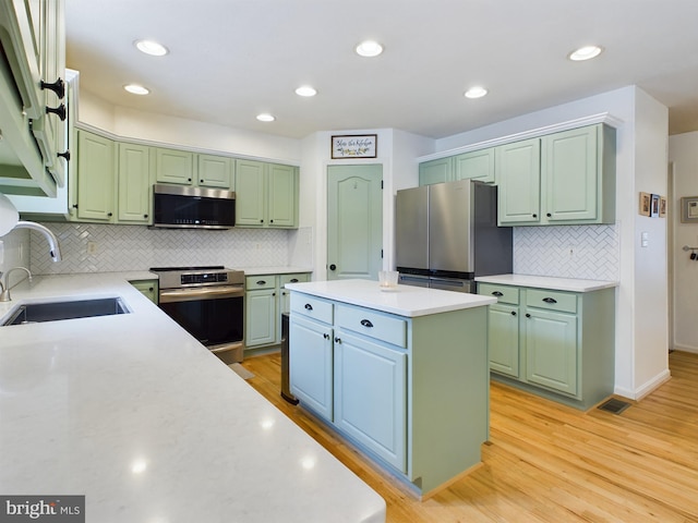 kitchen featuring stainless steel appliances, a kitchen island, green cabinets, and sink