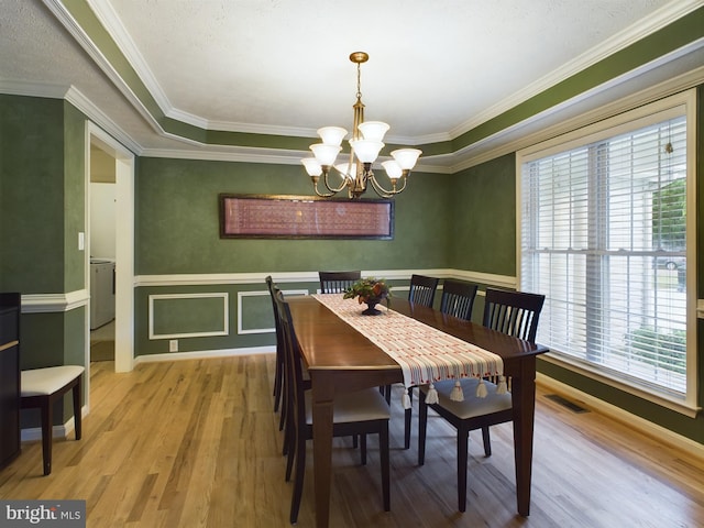 dining space featuring wood-type flooring, ornamental molding, a wealth of natural light, and a chandelier