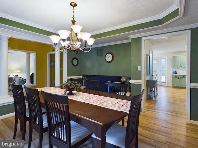 dining area with decorative columns, a textured ceiling, crown molding, an inviting chandelier, and light hardwood / wood-style floors