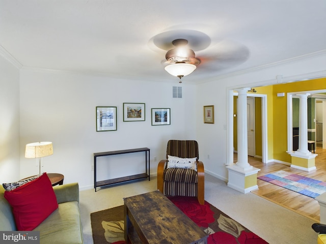 living room featuring ornate columns, crown molding, and light carpet