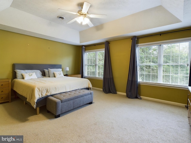 carpeted bedroom with a tray ceiling and ceiling fan