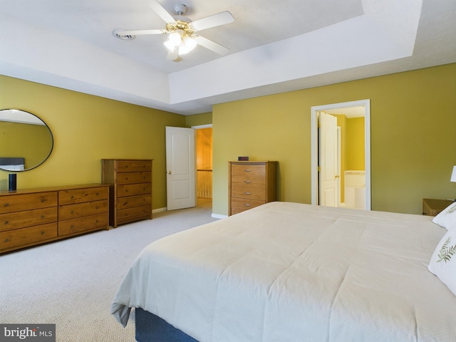 bedroom featuring ceiling fan, a raised ceiling, light carpet, and ensuite bath