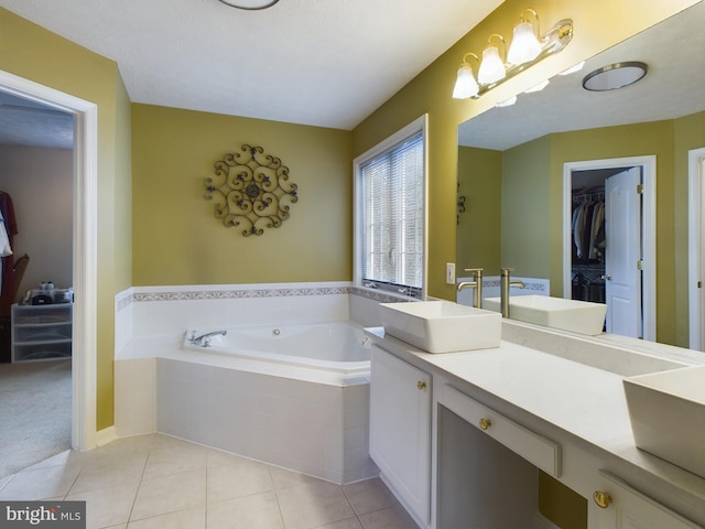 bathroom featuring vanity, a relaxing tiled tub, and tile patterned floors