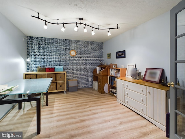 office space with a textured ceiling, light hardwood / wood-style floors, and brick wall