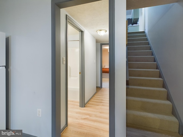 staircase featuring wood-type flooring and a textured ceiling