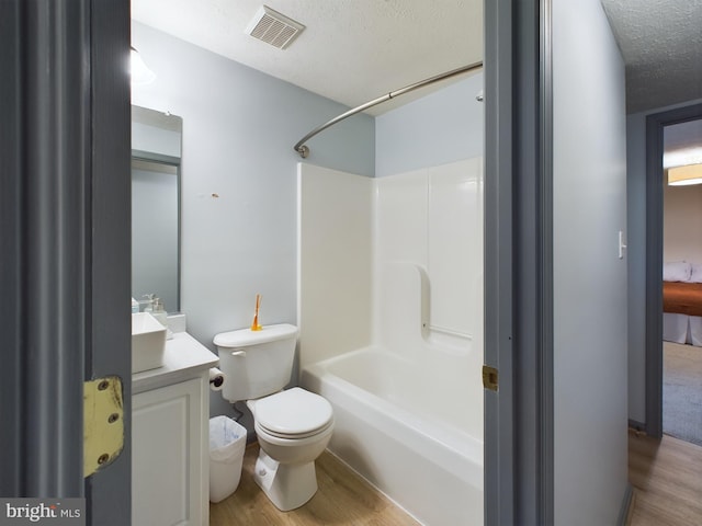 full bathroom with a textured ceiling, vanity, shower / tub combination, hardwood / wood-style floors, and toilet