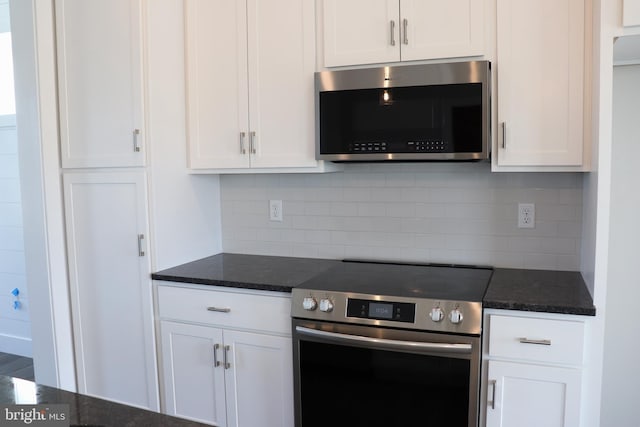 kitchen with tasteful backsplash, stainless steel appliances, dark stone countertops, and white cabinets