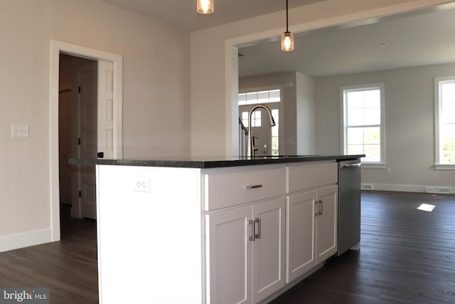 kitchen with sink, a kitchen island with sink, hanging light fixtures, and white cabinets