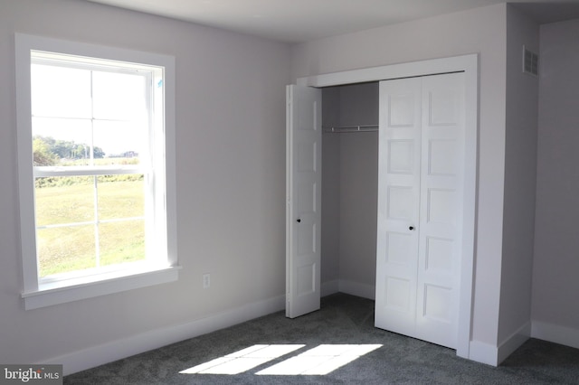 unfurnished bedroom featuring dark colored carpet and a closet