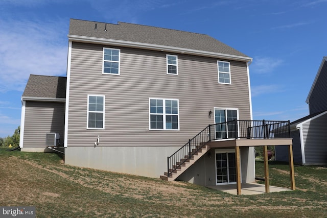 rear view of house featuring a patio, a wooden deck, a lawn, and central air condition unit