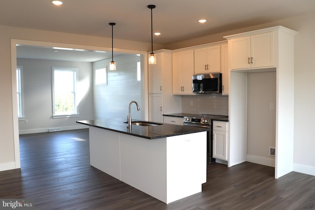 kitchen with an island with sink, stainless steel appliances, sink, and white cabinets