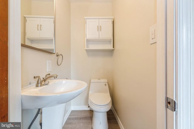 bathroom with hardwood / wood-style floors, toilet, and sink