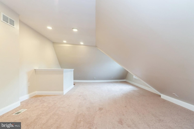 bonus room with light colored carpet and vaulted ceiling