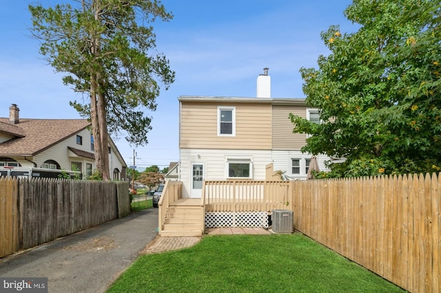 rear view of property featuring central AC, a yard, and a deck