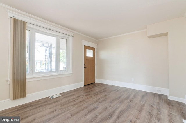 foyer entrance with light hardwood / wood-style floors and ornamental molding