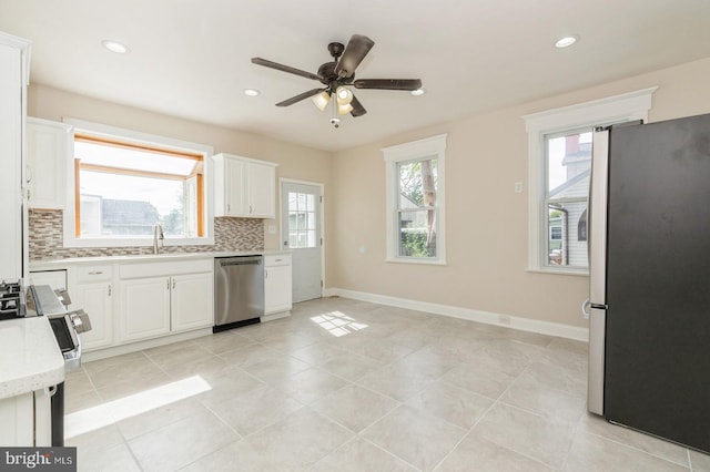 kitchen featuring appliances with stainless steel finishes, backsplash, ceiling fan, sink, and white cabinets