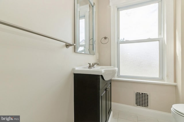 bathroom with vanity, a healthy amount of sunlight, and toilet