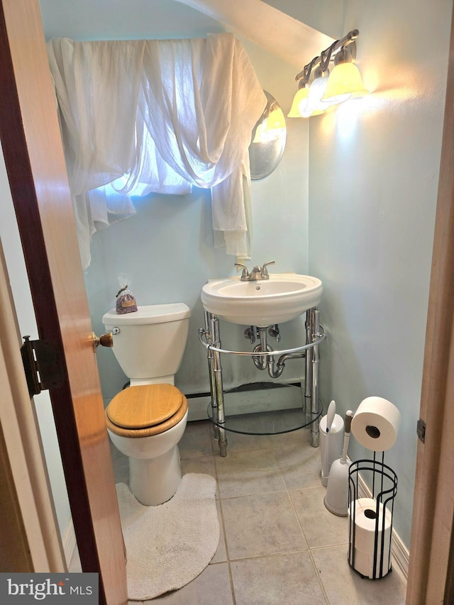 bathroom with a baseboard heating unit, baseboards, toilet, and tile patterned floors