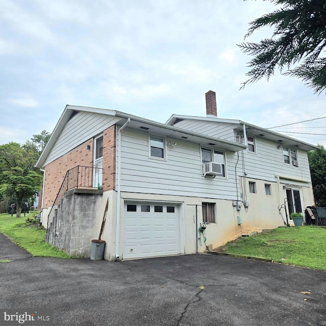 rear view of house featuring a garage, cooling unit, and a yard