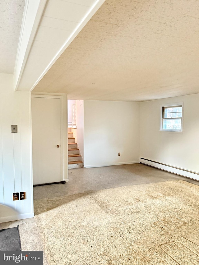 empty room with a baseboard radiator, stairs, and baseboards