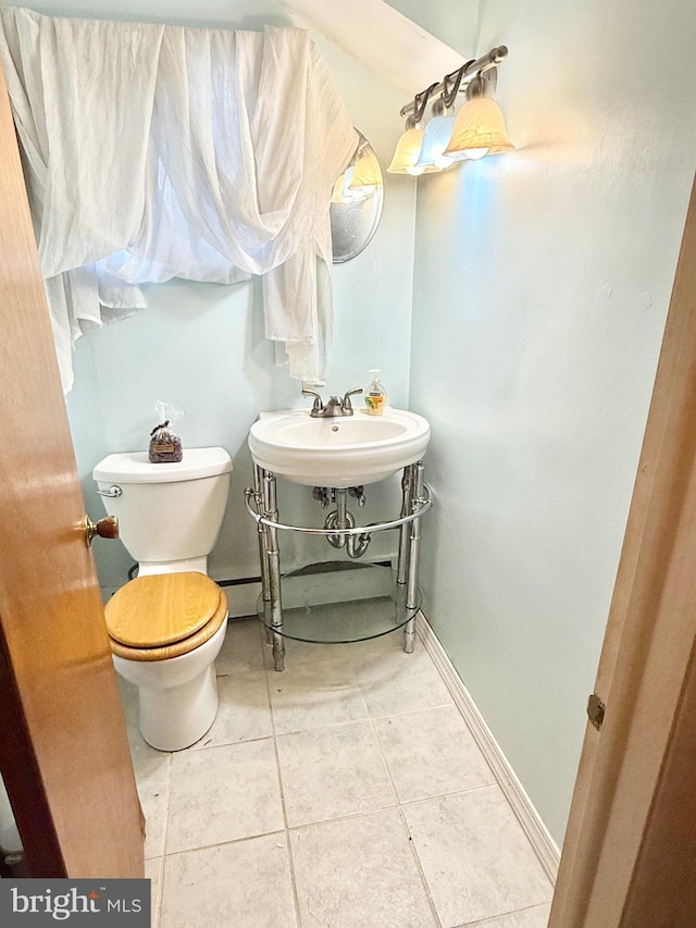 bathroom featuring toilet, baseboards, a sink, and tile patterned floors