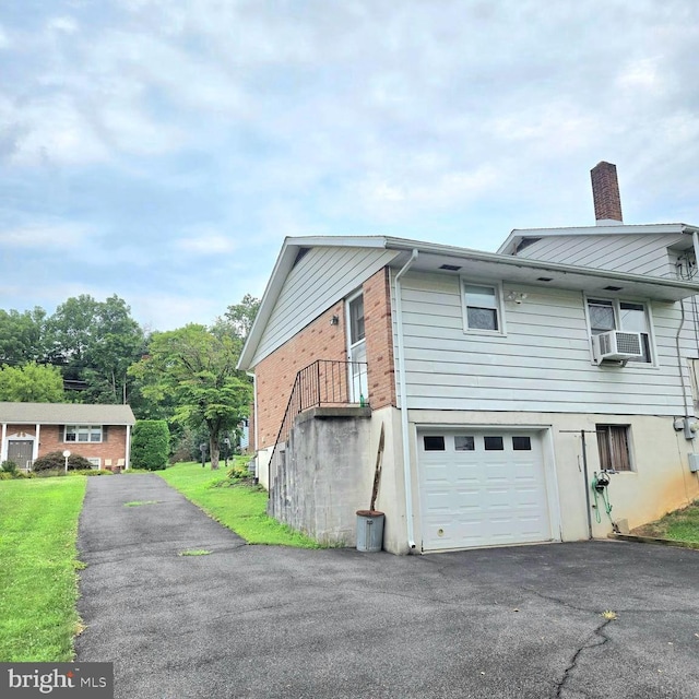 view of home's exterior with driveway, a chimney, an attached garage, cooling unit, and brick siding