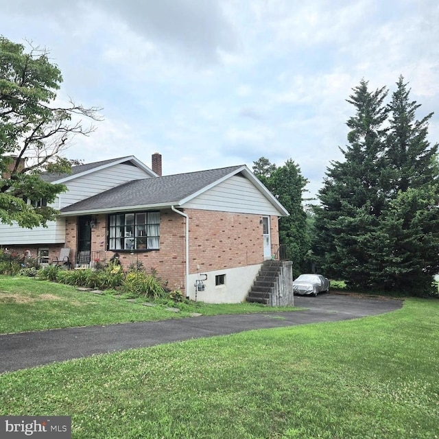 view of home's exterior featuring roof with shingles, a chimney, a lawn, and brick siding