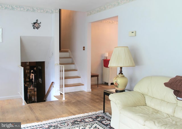 living room featuring stairs, baseboards, and wood finished floors